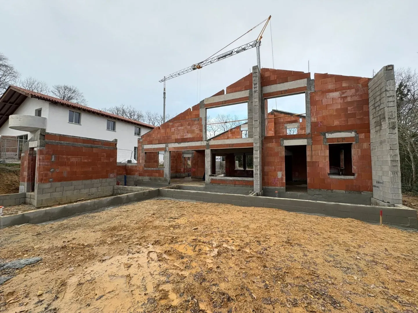 Façade de la maison neuve une fois les murs montés, ouvertures et linteaux en place