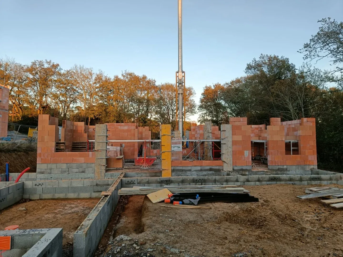 Murs en brique montés sur soubassement béton, grue au-dessus du chantier